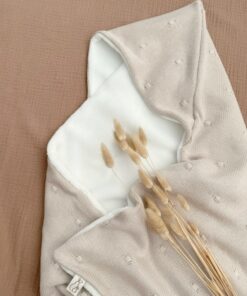 Het perfecte kraamcadeau! Een omslagdoek welke te gebruiken is als Mushie wikkeldeken in een zachte bamboe teddy met zandkleurige gebreide stip.